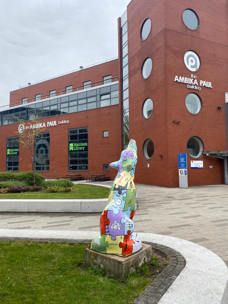 Image showing a collaged wolf statue in front of the Ambika Paul building housing the University of Wolverhampton Library