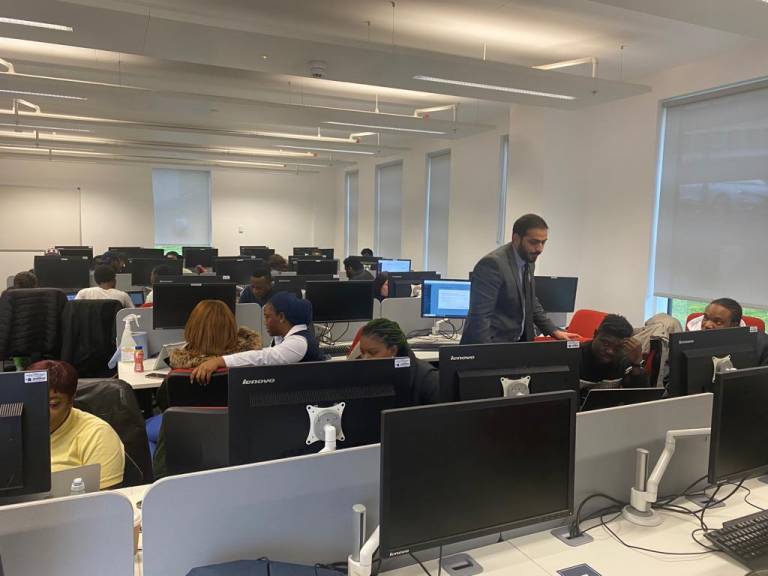 Image of Wolverhampton Senior Digital Marketing Lecturer, Dr. Imran assisting a student during his class at the university of wolverhampton computer lab